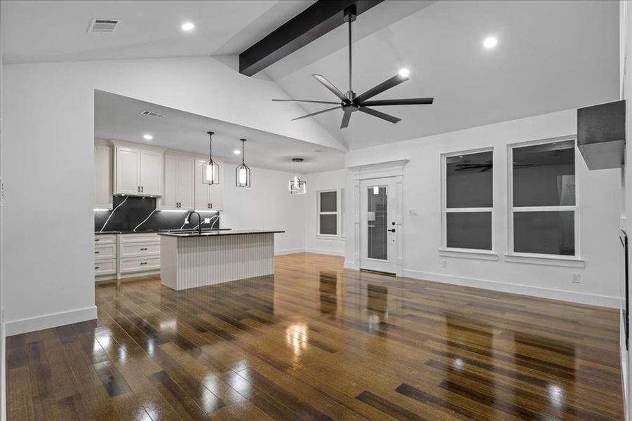 Kitchen with dark countertops, off-white cabinetry, kitchen island, wood-style flooring, open floor plan perfect for entertaining. Kitchen with dark countertops, off-white cabinetry, kitchen island, wood-style flooring, open floor plan perfect for entertaining.