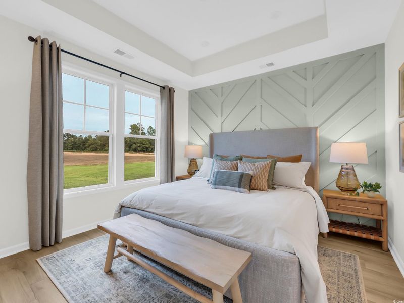 Bedroom featuring light wood-type flooring and a raised ceiling Bedroom featuring light wood-type flooring and a raised ceiling