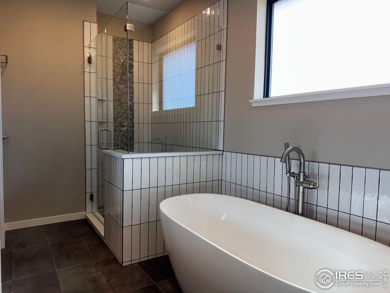 Primary bathroom with soaking tub and beautifully tiled shower. Heated ceramic tile floors. All 3 full bathrooms have heated floors!