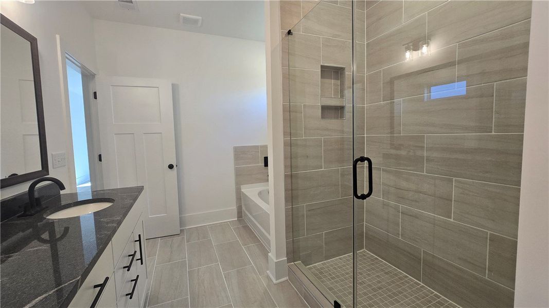 Luxurious master bathroom features a spacious glas