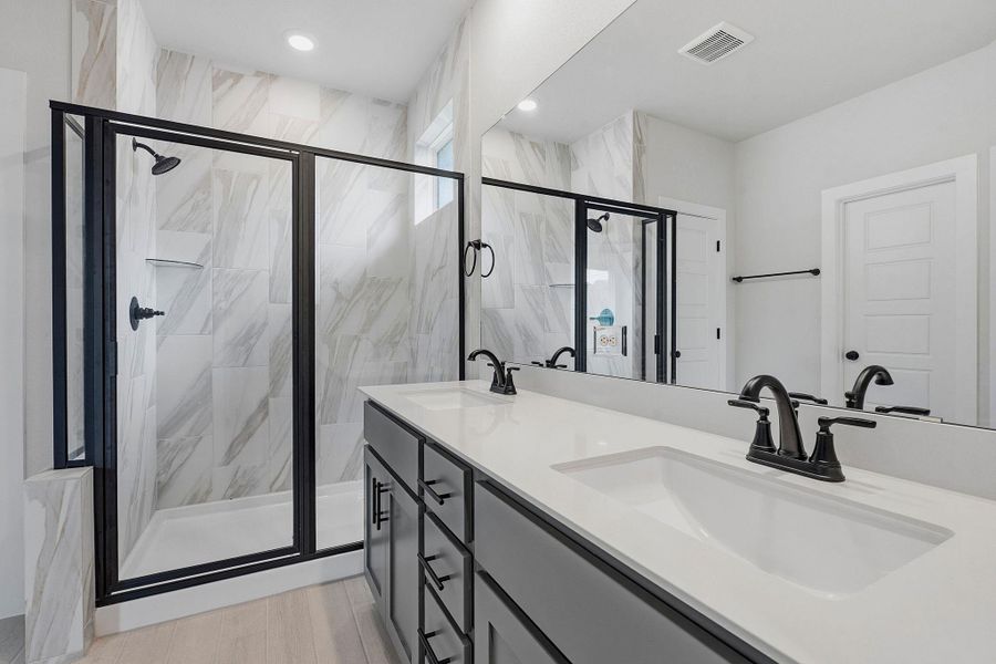 Dual vanities and a spacious walk-in shower elevate this pristine, contemporary bathroom.