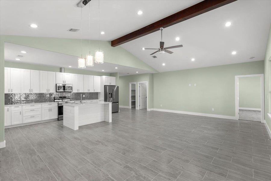 Kitchen with backsplash, beam ceiling, pendant lighting, white cabinetry, and open floor plan