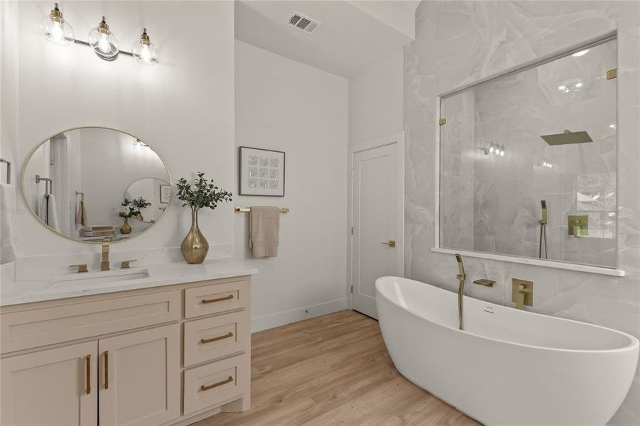 Bathroom with a marble finish shower, wood finished floors, vanity, a freestanding tub, and baseboards Bathroom with a marble finish shower, wood finished floors, vanity, a freestanding tub, and baseboards