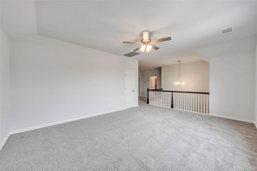 Empty room with vaulted ceiling, a ceiling fan, a chandelier, and carpet flooring Empty room with vaulted ceiling, a ceiling fan, a chandelier, and carpet flooring