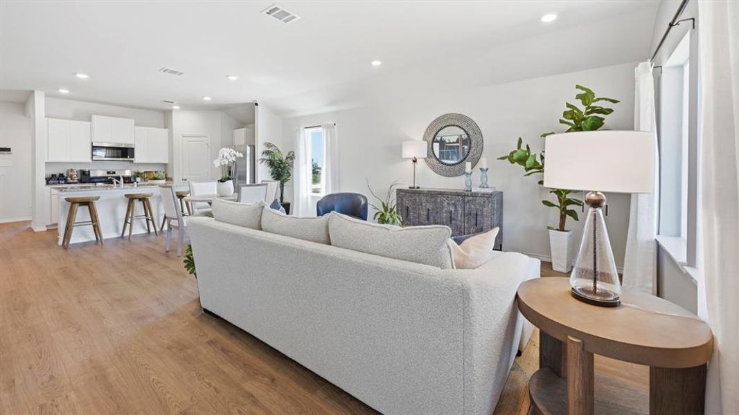 Open concept living area featuring light wood-tone flooring, recessed lighting, and large windows providing natural light