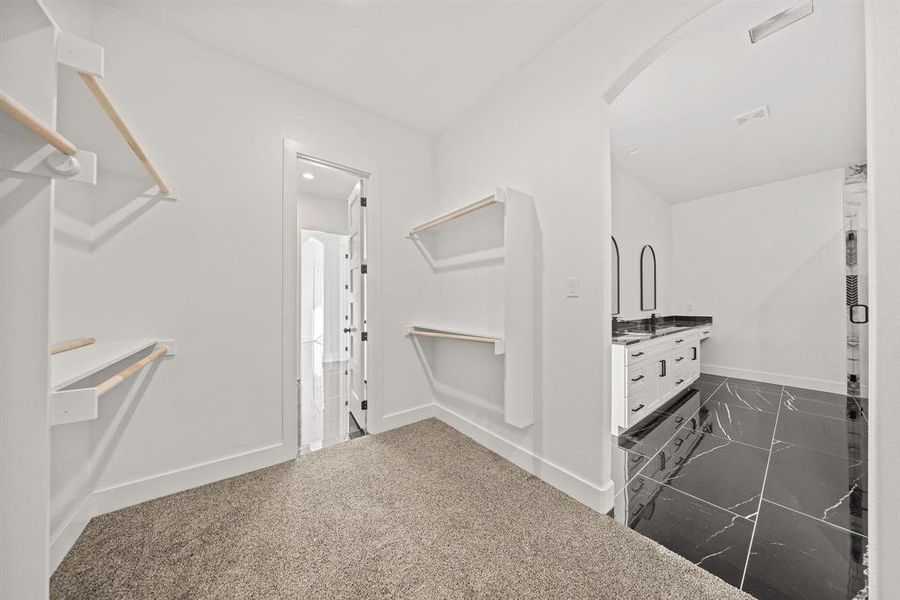 Spacious closet featuring arched walkways and dark marble finish flooring Spacious closet featuring arched walkways and dark marble finish flooring