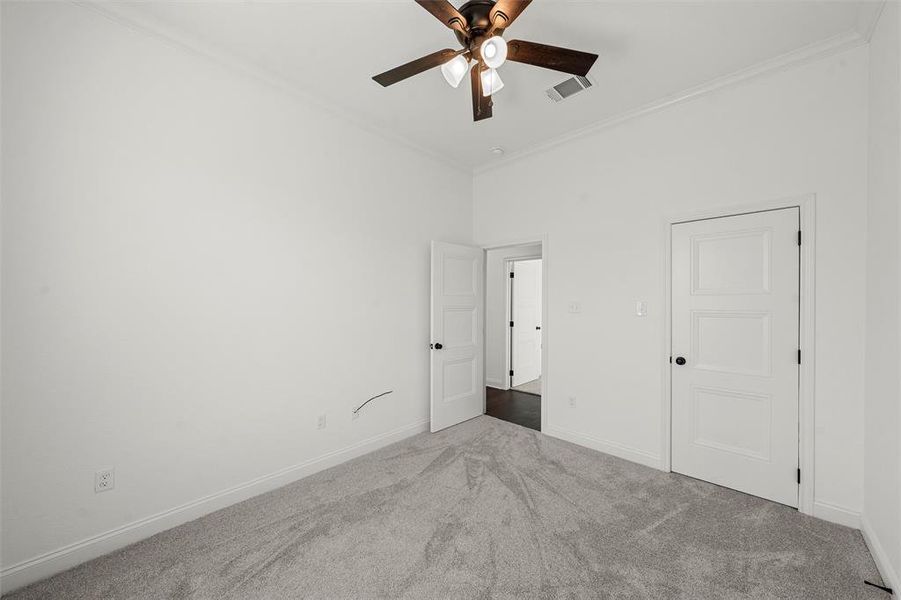 Unfurnished bedroom with carpet, ornamental molding, and a ceiling fan Unfurnished bedroom with carpet, ornamental molding, and a ceiling fan