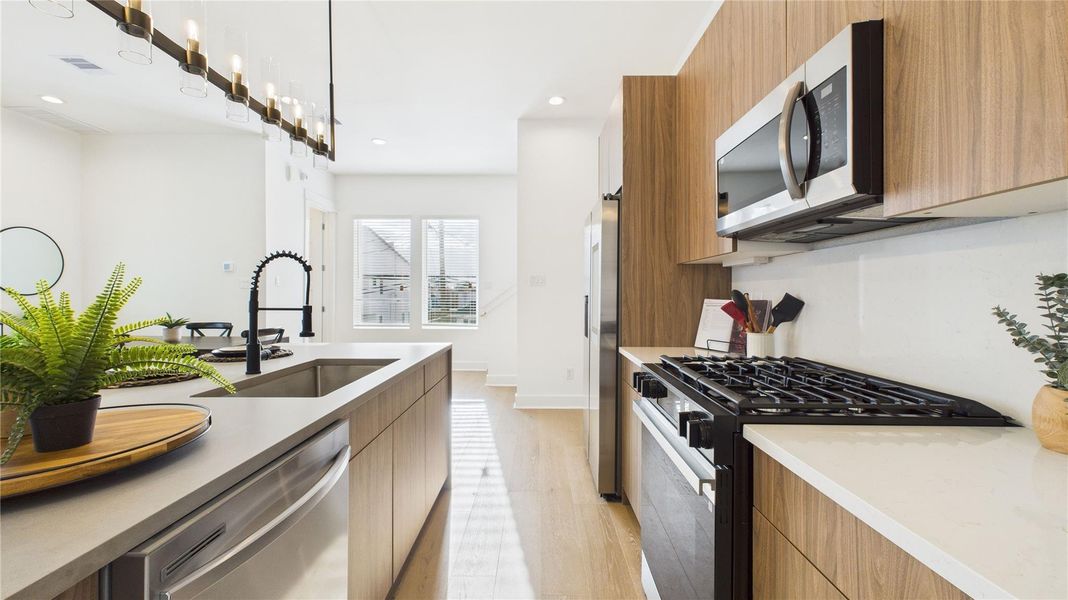 The kitchen is equipped with sleek, modern cabinets, offering ample storage while maintaining a clean, contemporary look; perfect for keeping everything organized and stylish in the heart of the open concept living space.