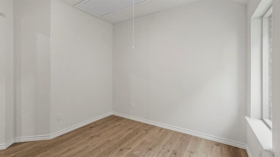 Room featuring light wood-finish flooring, white baseboards, and a tall window with a white frame