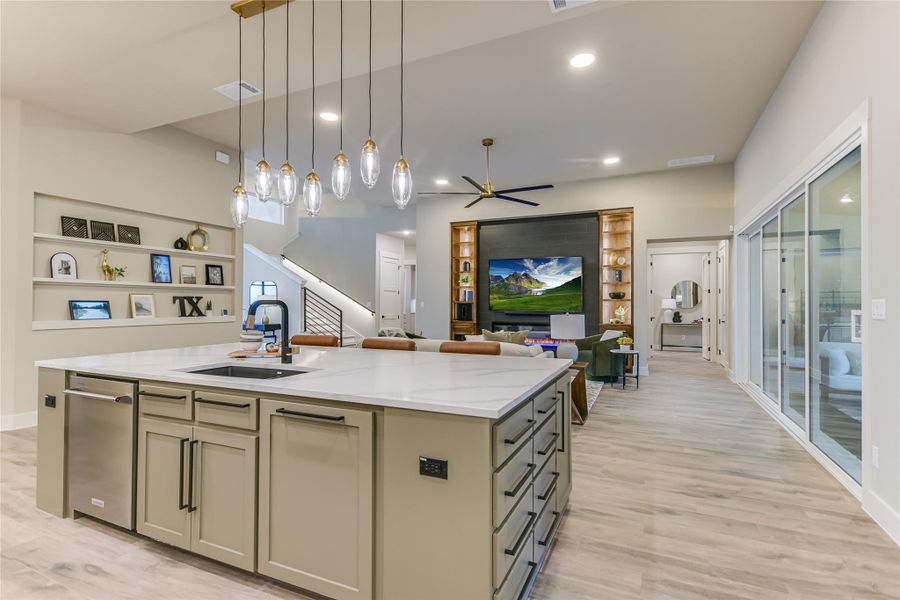 Kitchen featuring a center island with sink, pendant lighting, light stone counters, open floor plan Kitchen featuring a center island with sink, pendant lighting, light stone counters, open floor plan