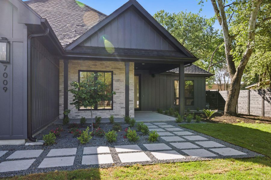 View of front of house with board and batten siding, covered porch, brick siding, and a shingled roof