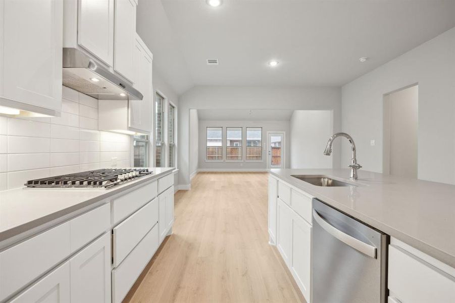 Kitchen with appliances with stainless steel finishes, white cabinetry, sink, backsplash, and light wood-type flooring