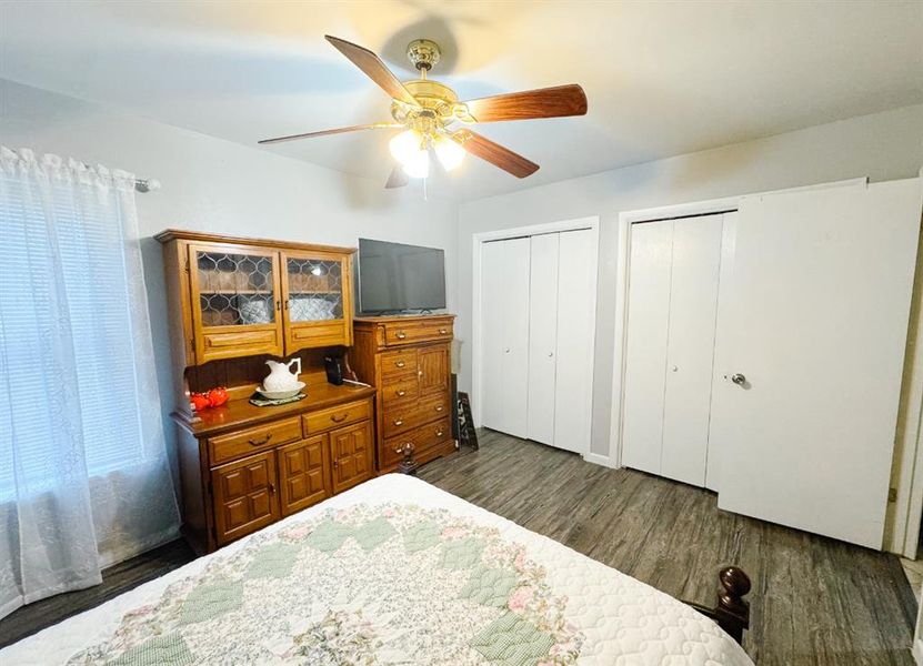 Bedroom featuring two closets, dark wood-style flooring, and ceiling fan