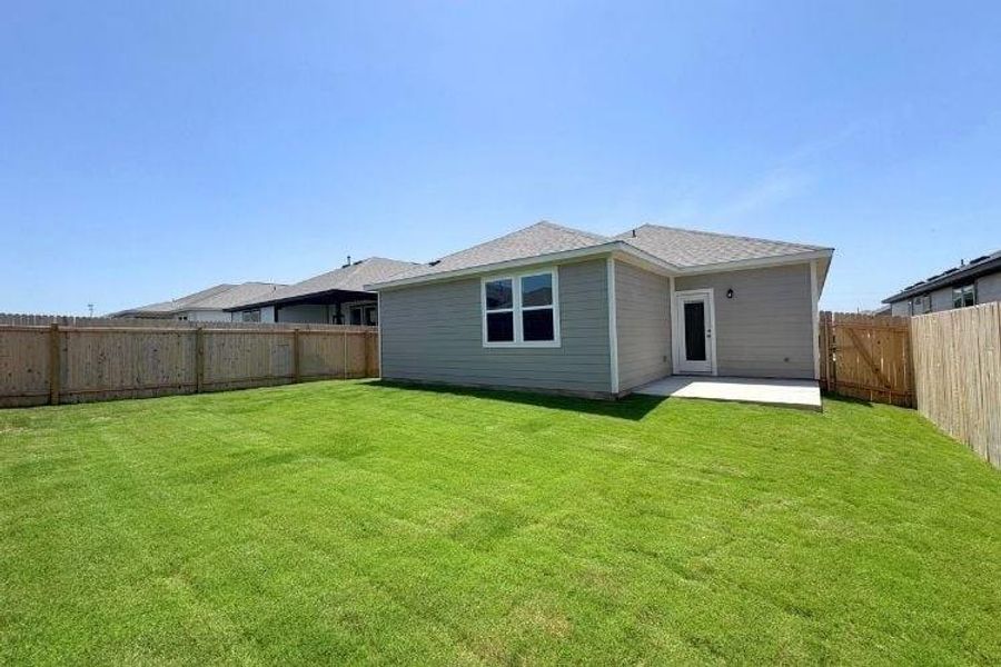 Rear view of house with a fenced backyard and a patio area