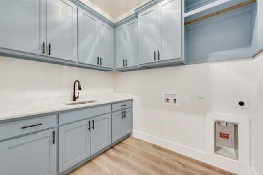 Clothes washing area with washer hookup, hookup for an electric dryer, sink, cabinets, and light hardwood / wood-style floors