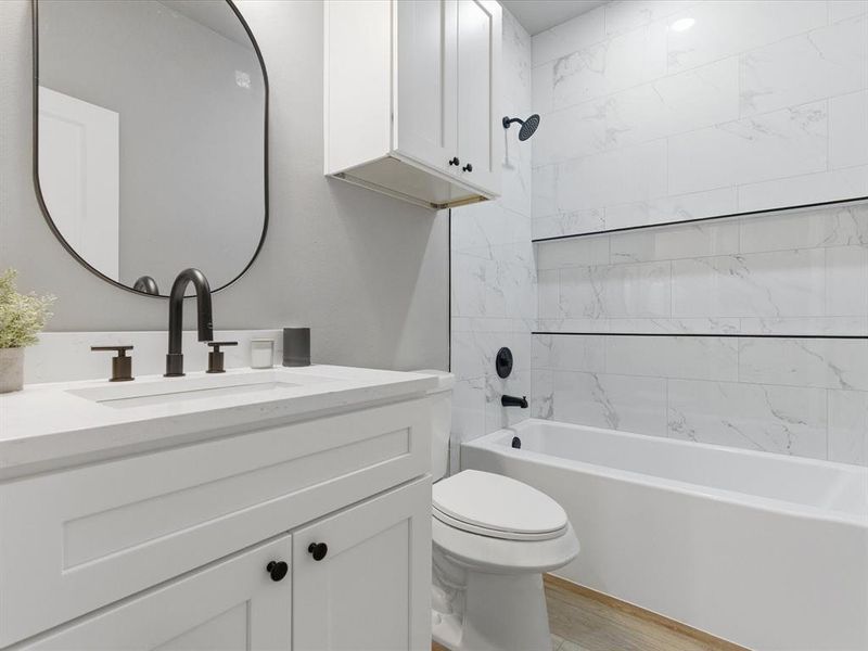 Full bath featuring shower combination, vanity, and light wood-type flooring Full bath featuring shower combination, vanity, and light wood-type flooring