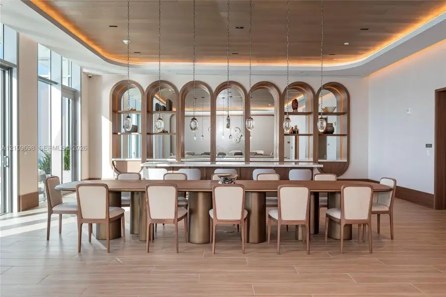 Recessed cove lighting, wood-paneled ceiling, arched built-in shelving with integrated mirrors, floor-to-ceiling windows, and wood-finish tile flooring