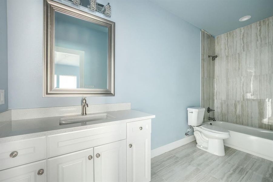 Full bathroom featuring vanity, tiled shower / bath combo, and toilet