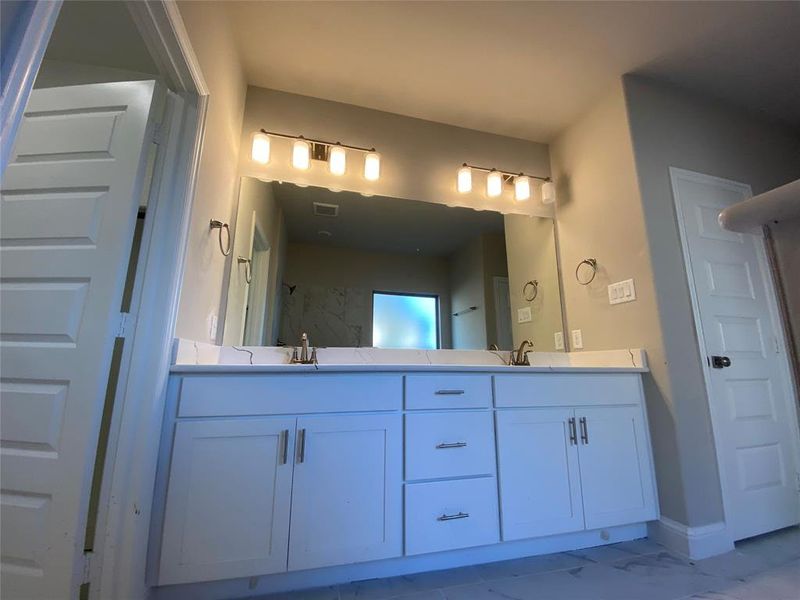 Master bath vanity has white Shaker cabinets, Monet Quartz counters, and decorative