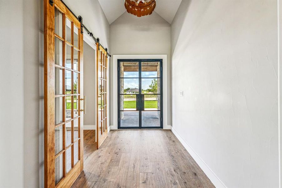 Doorway featuring hardwood / wood-style flooring, french doors, a barn door, and high vaulted ceiling