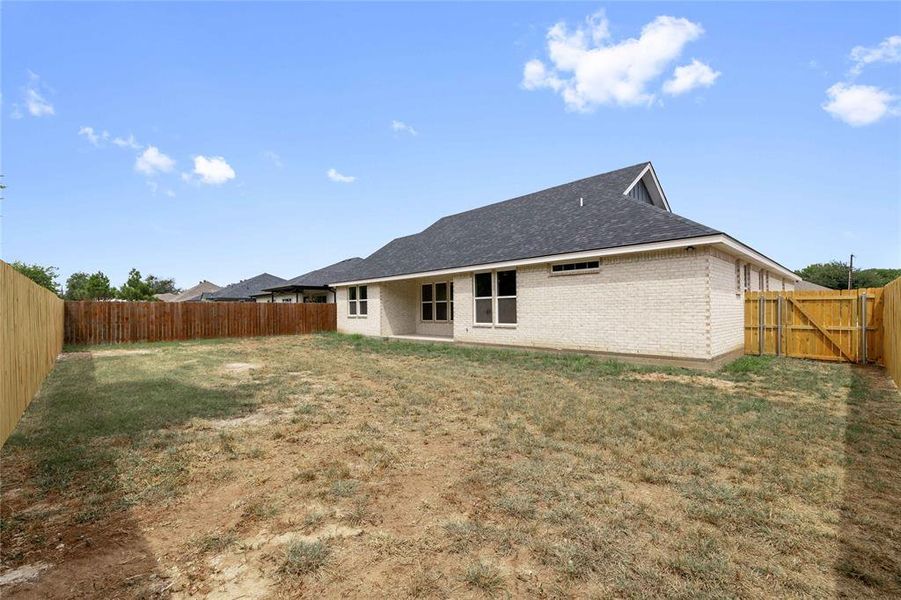Rear view of house with a patio area, a fenced backyard, brick siding, a shingled roof, and a gate Rear view of house with a patio area, a fenced backyard, brick siding, a shingled roof, and a gate