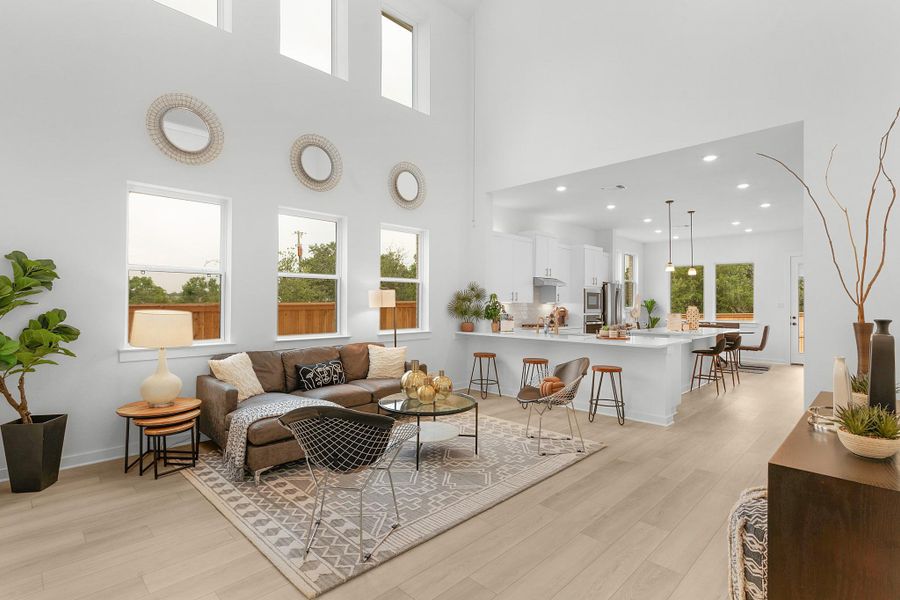Living room with light wood-style flooring, healthy amount of natural light, a towering ceiling, recessed lighting, and baseboards