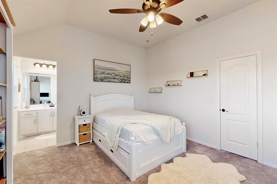 Bedroom featuring light colored carpet, a ceiling fan, vaulted ceiling, and ensuite bathroom