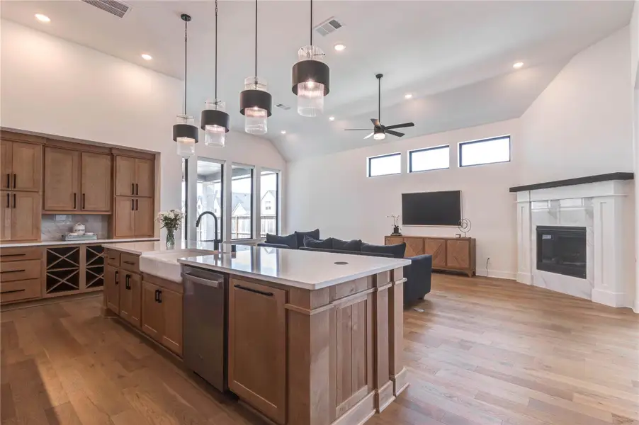 This modern living space features an open floor plan with a spacious kitchen island, elegant pendant lighting, and a cozy living area with a fireplace. Large windows provide natural light, enhancing the airy feel. This modern living space features an open floor plan with a spacious kitchen island, elegant pendant lighting, and a cozy living area with a fireplace. Large windows provide natural light, enhancing the airy feel.