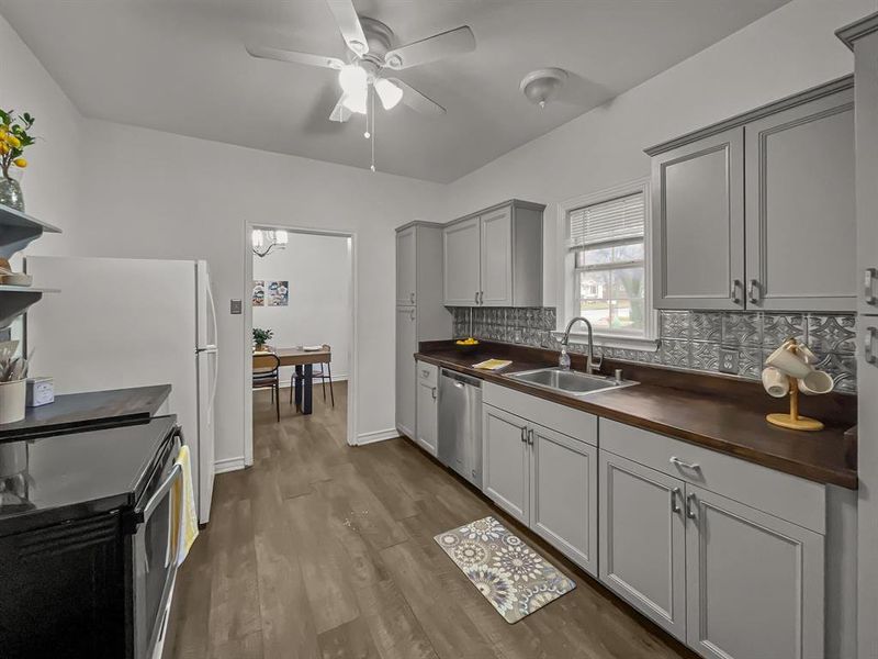 Kitchen with dishwasher, wood counters, range with electric cooktop, sink, gray cabinets, and decorative backsplash