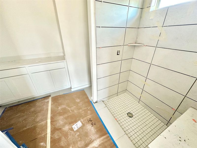 Full bath featuring light tile patterned floors, vanity, and a stall shower