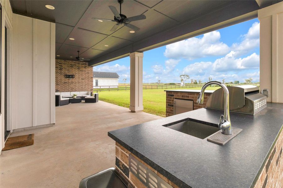 Expansive covered patio with comfortable seating area and scenic back yard views.