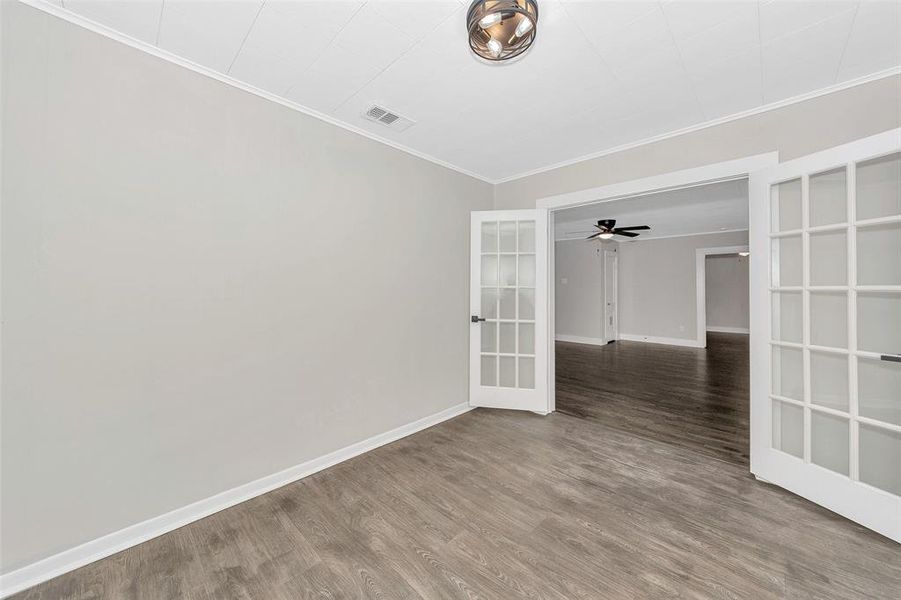 Spare room with baseboards, wood finished floors, visible vents, and crown molding