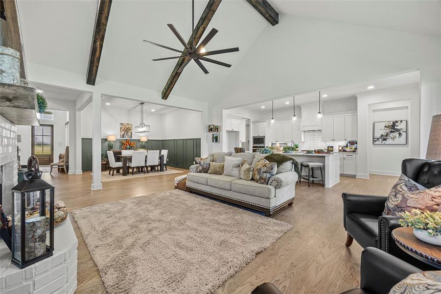 Living room with high vaulted ceiling, ceiling fan, light hardwood / wood-style floors, and beam ceiling