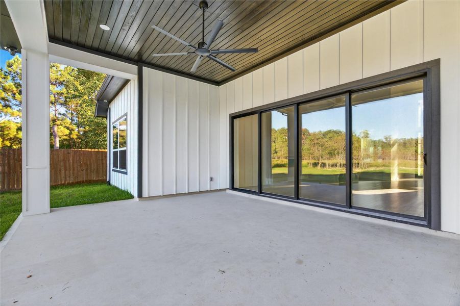 Expansive covered outdoor living area features a wood-accented ceiling and oversized sliding doors connecting directly to the interior. **Images are from a previously completed project. **