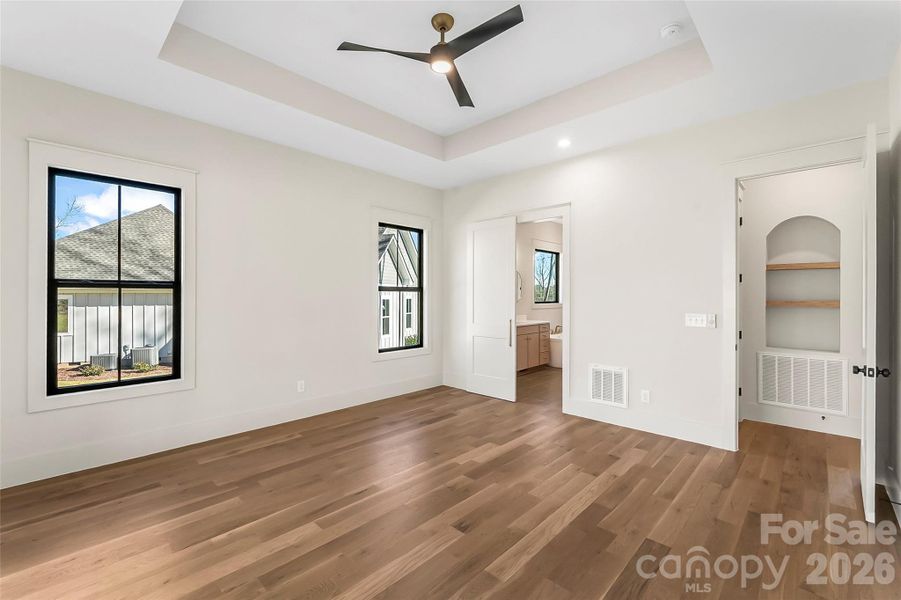 The primary bedroom tucked off away on the main level is your own private sanctuary and it overlooks the wooded backyard.