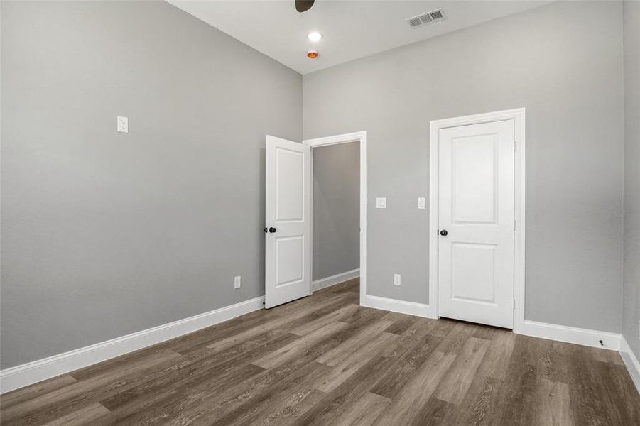 Unfurnished bedroom with wood finished floors and a towering ceiling Unfurnished bedroom with wood finished floors and a towering ceiling