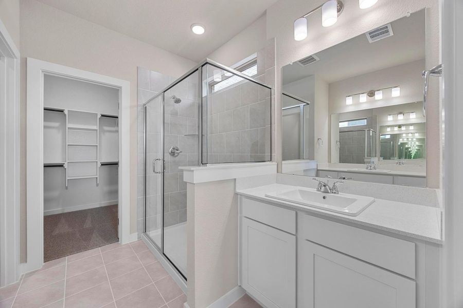 A well-appointed primary bathroom features a spacious glass-enclosed shower, a large vanity, and an adjoining walk-in closet. A well-appointed primary bathroom features a spacious glass-enclosed shower, a large vanity, and an adjoining walk-in closet.