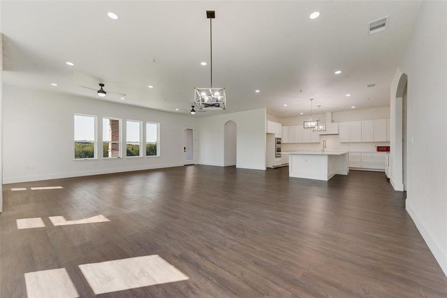 Spacious open-concept living area featuring wood-finish flooring, recessed lighting, and multiple large windows Spacious open-concept living area featuring wood-finish flooring, recessed lighting, and multiple large windows