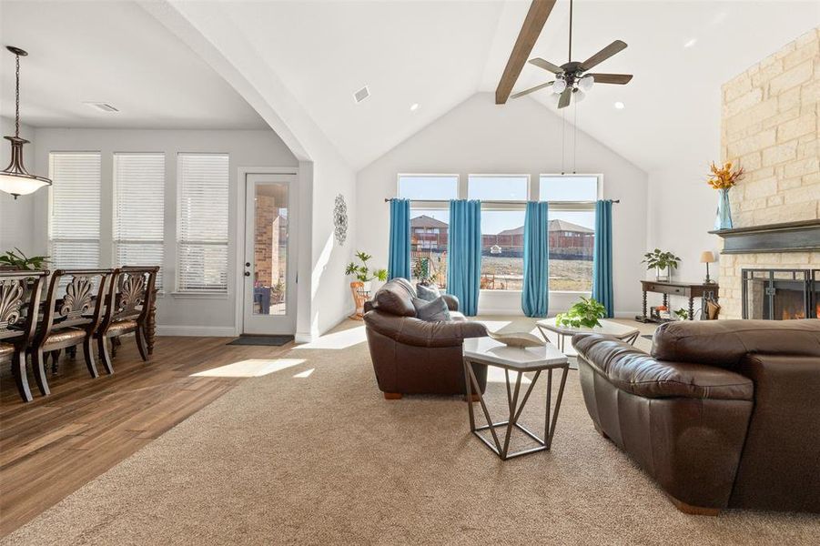Living room with hardwood / wood-style flooring, ceiling fan, lofted ceiling with beams, and a stone fireplace Living room with hardwood / wood-style flooring, ceiling fan, lofted ceiling with beams, and a stone fireplace