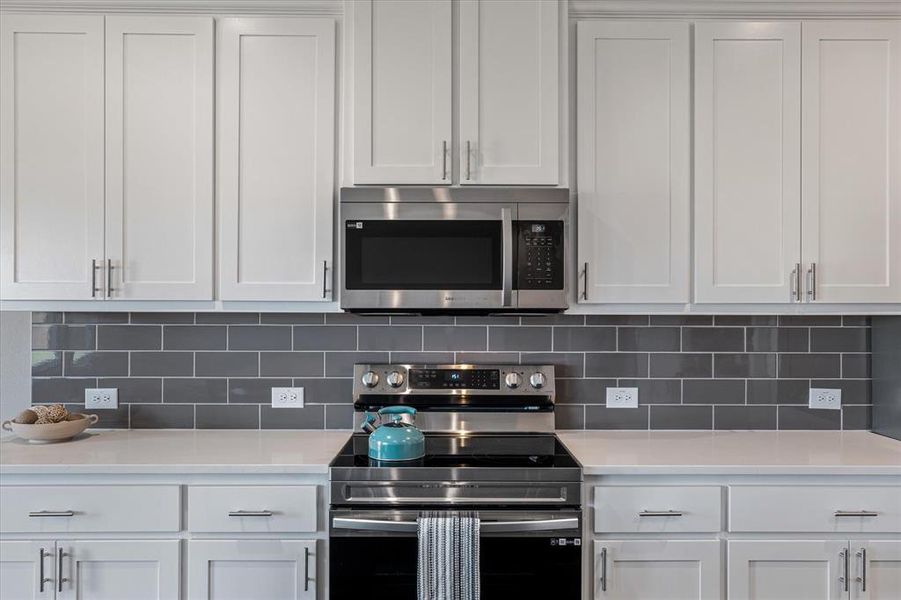Kitchen featuring white cabinets, decorative backsplash, and stainless steel appliances Kitchen featuring white cabinets, decorative backsplash, and stainless steel appliances