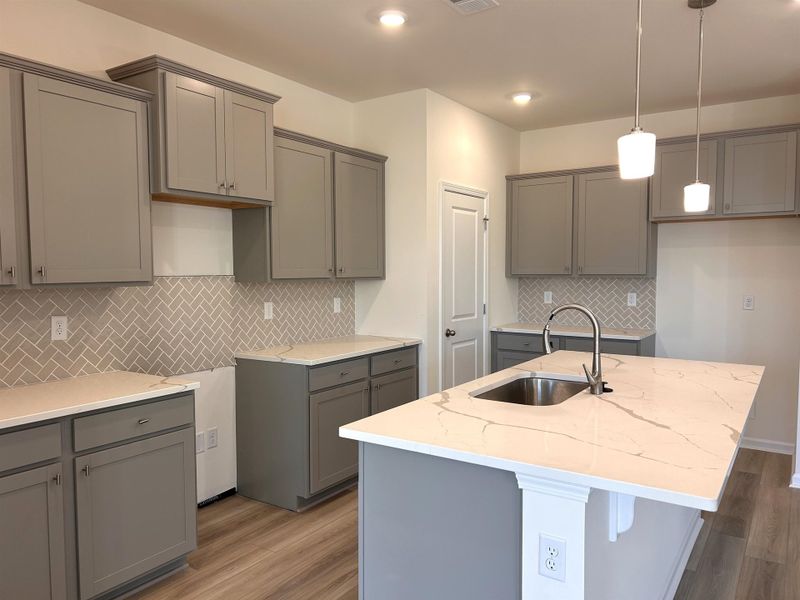 Kitchen with gray cabinetry, light stone counters, and tasteful backsplash