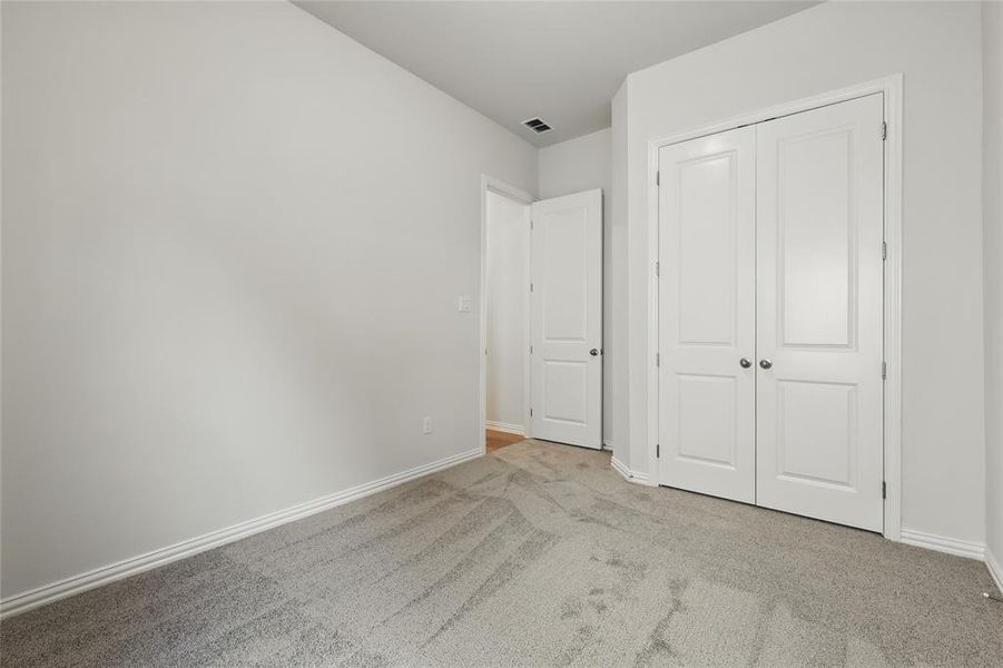 Unfurnished bedroom featuring light carpet and a closet