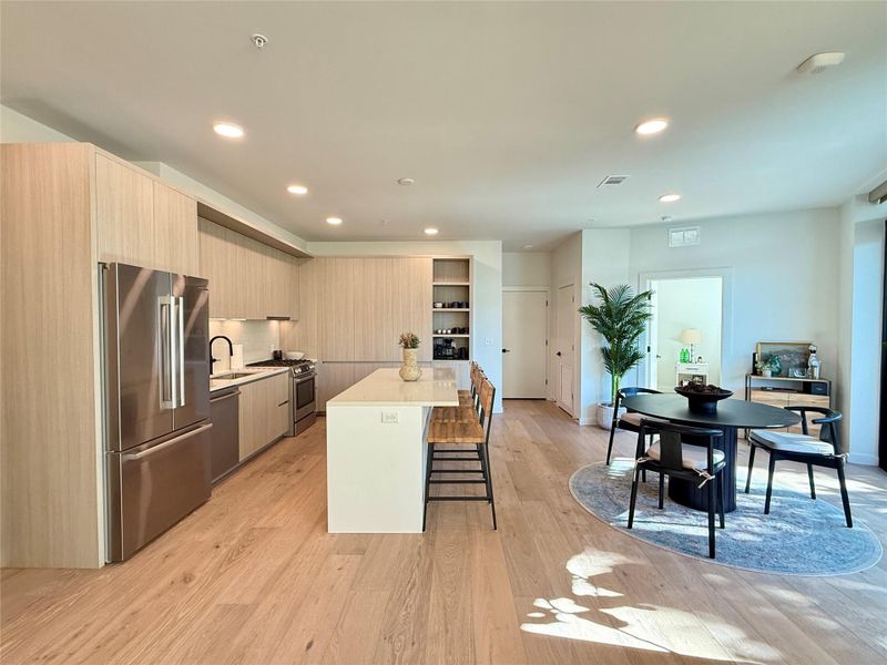 Modern kitchen with streamlined cabinetry flows into a dedicated dining area.
