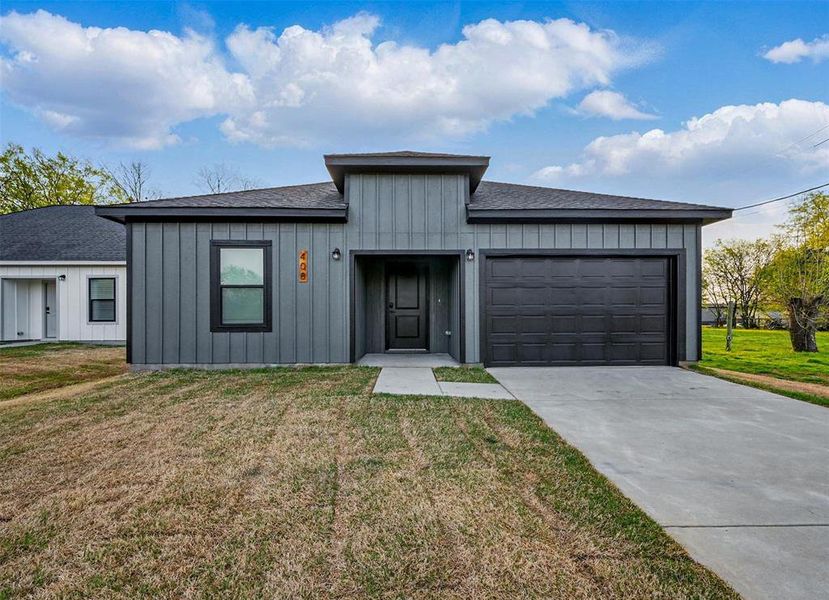 View of front of property with a front yard, a garage, board and batten siding, and concrete driveway View of front of property with a front yard, a garage, board and batten siding, and concrete driveway