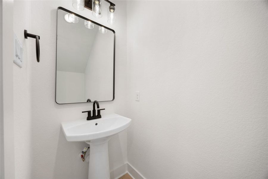 The powder room on the first floor includes a pedestal sink, mirror, sleek and modern fixtures--all to conveniently meet your needs.