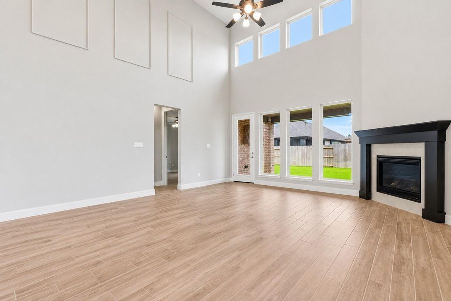 The impressive living room showcases soaring 20-foot ceilings, a cozy fireplace with a beautiful wood mantel, and a dramatic wall of windows that fills the space with natural light.  Primary bedroom is to the left.