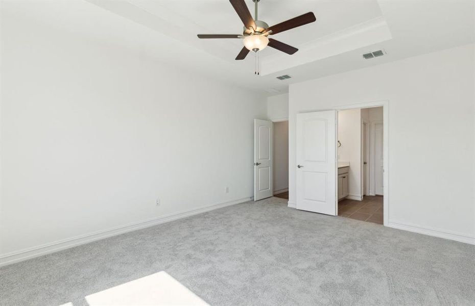 Owner's suite featuring large windows and a sophisticated tray ceiling *Real home pictured Owner's suite featuring large windows and a sophisticated tray ceiling *Real home pictured