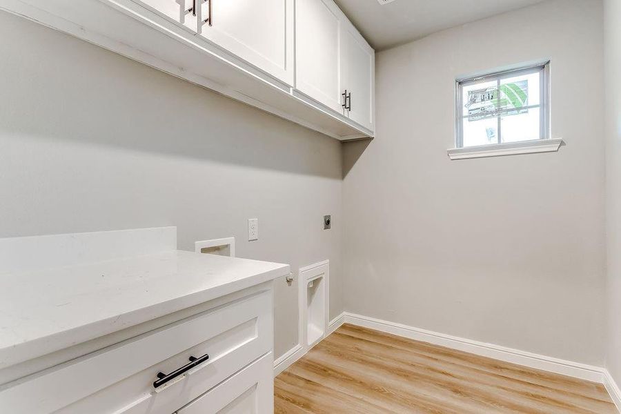 Laundry room featuring hookup for an electric dryer, cabinets, light wood-type flooring, and hookup for a washing machine