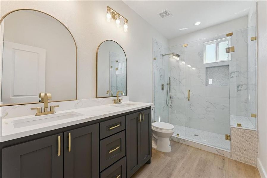 Full bath featuring double vanity, light wood-style flooring, a marble finish shower, and recessed lighting