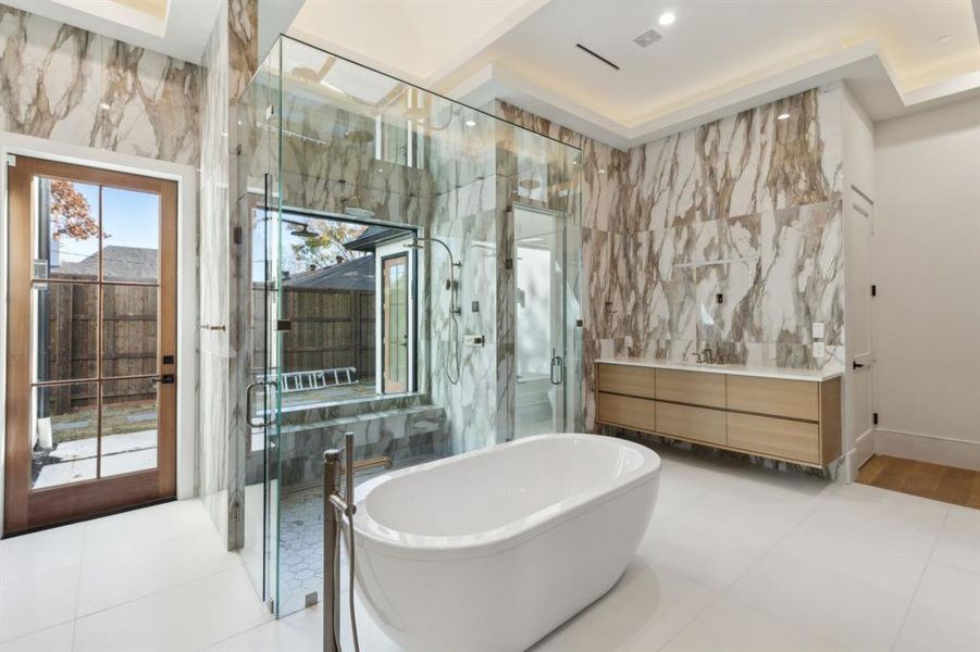 Full bathroom with tile walls, a freestanding bath, vanity, a marble finish shower, and light tile patterned flooring